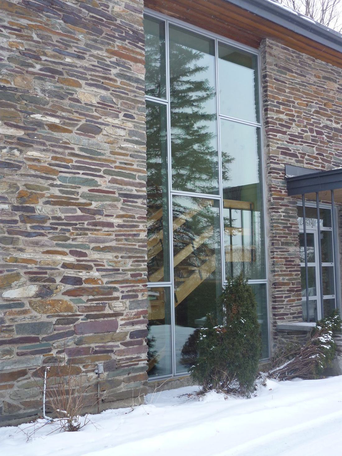 Tall aluminum-framed windows set into a stone facade in winter